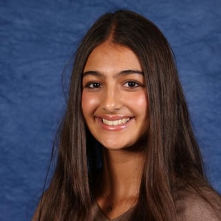 Portrait of a smiling young woman with long dark hair against a blue background